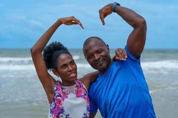 Joyful family enjoys sunny day at beach, creating heart shapes with their arms, celebrating love...