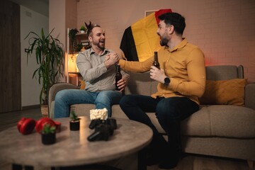 Obraz premium Friends enjoying a lively evening gathering with drinks and laughter in a cozy living room adorned with colorful decorations