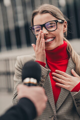 Confident woman in formal suit smiling during business interview outside urban setting on a sunny...
