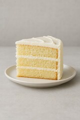 Slice of vanilla layer cake with white cream frosting served on plate close up view of sweet dessert