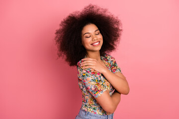 Attractive young woman with curly hair smiling confidently in stylish floral attire against a...