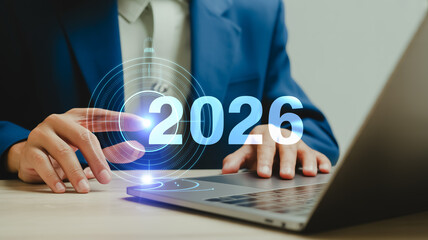 A professional business photo of hands typing on a silver laptop keyboard with a holographic 2026 number floating above the workspace.