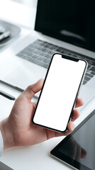 Close-up of a hand holding a smartphone with a blank white screen next to a laptop mobile phone person