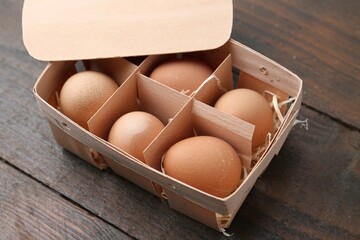Raw chicken eggs in egg tray on wooden table, closeup