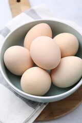 Raw chicken eggs in bowl on white table, closeup