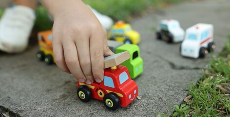 Fototapeta premium Little boy playing with toy cars outdoors, closeup