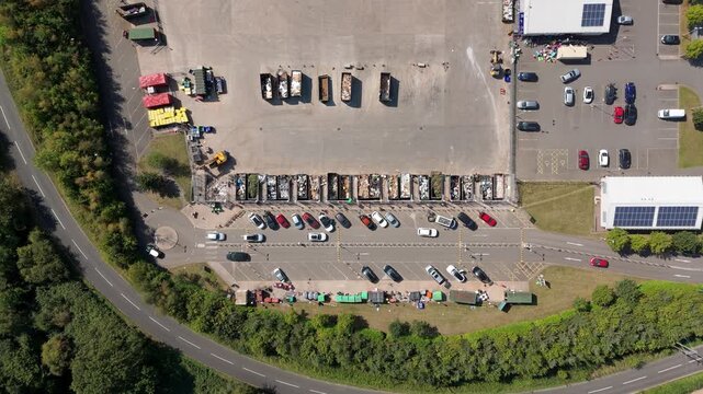 Top down aerial view of domestic waste recycling centre, unloading waste at refuse dump site into skips in England UK
