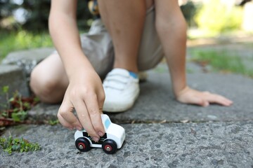 Naklejka premium Little boy playing with toy car outdoors, closeup