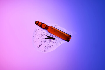 An ampoule with serum in its texture on a purple background with a leaf.