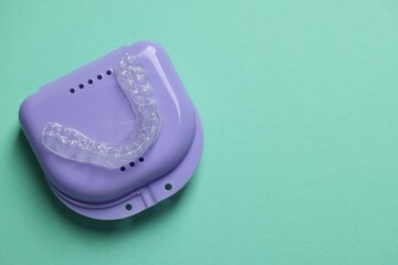 Clear aligner and retainer case on turquoise background, top view. Space for text