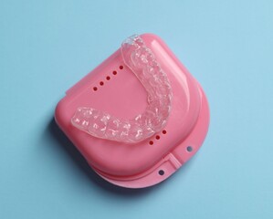 One clear aligner and retainer case on light blue background, top view