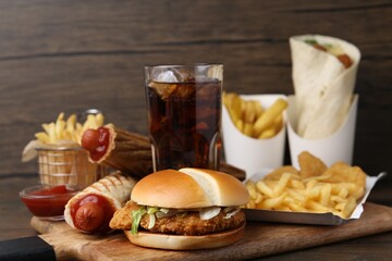 Different delicious fast food and cola on wooden table, closeup