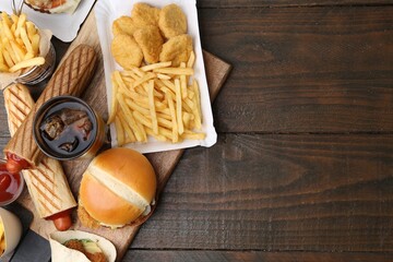 Different delicious fast food and cola on wooden table, flat lay. Space for text