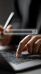 Close-up of a person's hand typing on a laptop keyboard with a digital search bar overlay interface