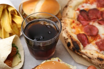 Different delicious fast food and cola on light grey textured table, closeup