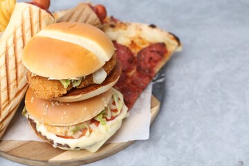 Different delicious fast food on grey table, closeup. Space for text