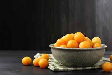 Ripe yellow cherry plums on black wooden table. Space for text