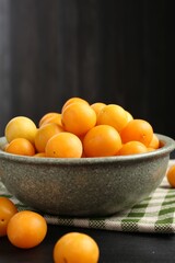 Ripe yellow cherry plums on black wooden table. Space for text