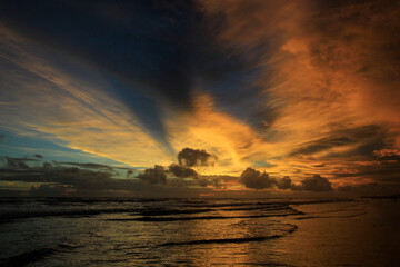 The dramatic afternoon sky on the beach, the sky burning with the tidal waves brings a restless atmosphere between beauty and something horrible.
