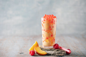 Cold iced peach raspberry bubble tea with juice balls in glass