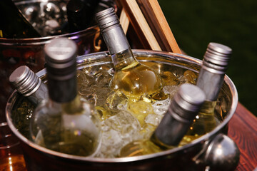Bottles of white wine and a champagne bottle chilling in a silver ice bucket at a party or event