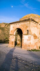 Old stone building with archway, under a partly cloudy sky