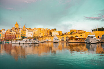 Spectacular view of the moored sailing yachts in seaport Vittoriosa and St. Lawrence's Catholic Church. Location place Birgu harbour, Malta, Europe. Photo wallpapers. Discovery the beauty of earth.