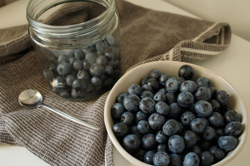 Fresh blueberries in the bowl and in glass jar on the kitchen table