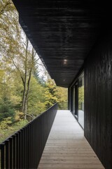 Modern black exterior creates a striking contrast with vibrant autumn foliage along a wooden balcony in a tranquil forest setting
