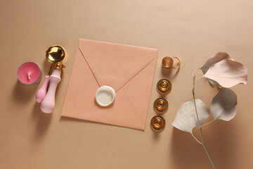 Wedding invitation stationery set. Envelope with sealing wax, vintage stamps and gold rings on beige background