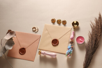Wedding invitation stationery set. Envelopes with sealing wax, vintage stamp and gold rings, dry grass on beige background