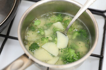 potatoes with broccoli are boiled in a saucepan on the stove