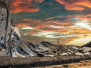 A scene of devastation, showcasing a destroyed building with a stunning sunset background.