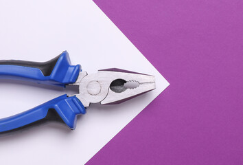 Pliers with blue handles on purple white background