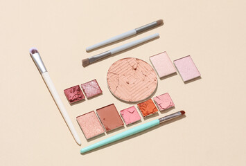 Crushed eyeshadow for makeup with brushes. Cosmetic product sample on beige background. Creative...