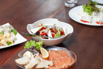 Restaurant dishes on the table. Caesar salad, cheese and salmon