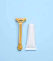 Razor with a tube of cream on a blue background