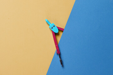Stationery Compasses in a blue yellow background. Top view
