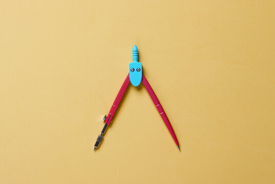 Stationery Compass on yellow background. Top view