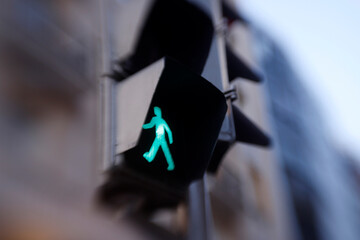 Green traffic light showing walking figure allowing pedestrians to cross road