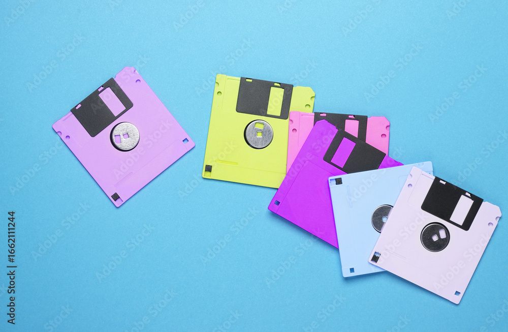 Poster many colored floppy disks on blue background. computer technology 80s. top view.