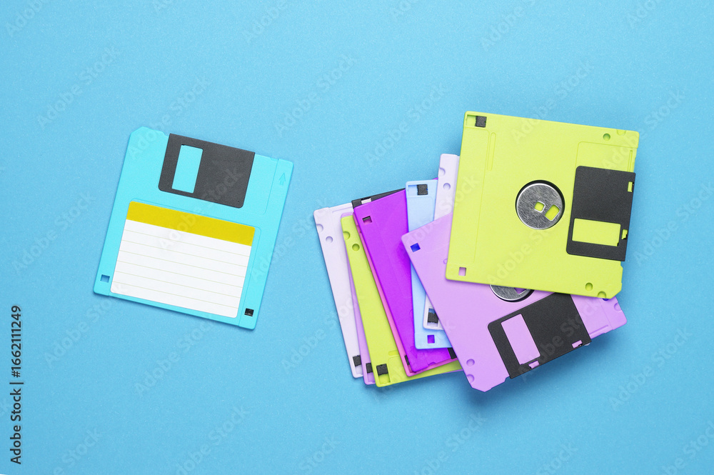 Poster many colored floppy disks on blue background. computer technology 80s. top view.