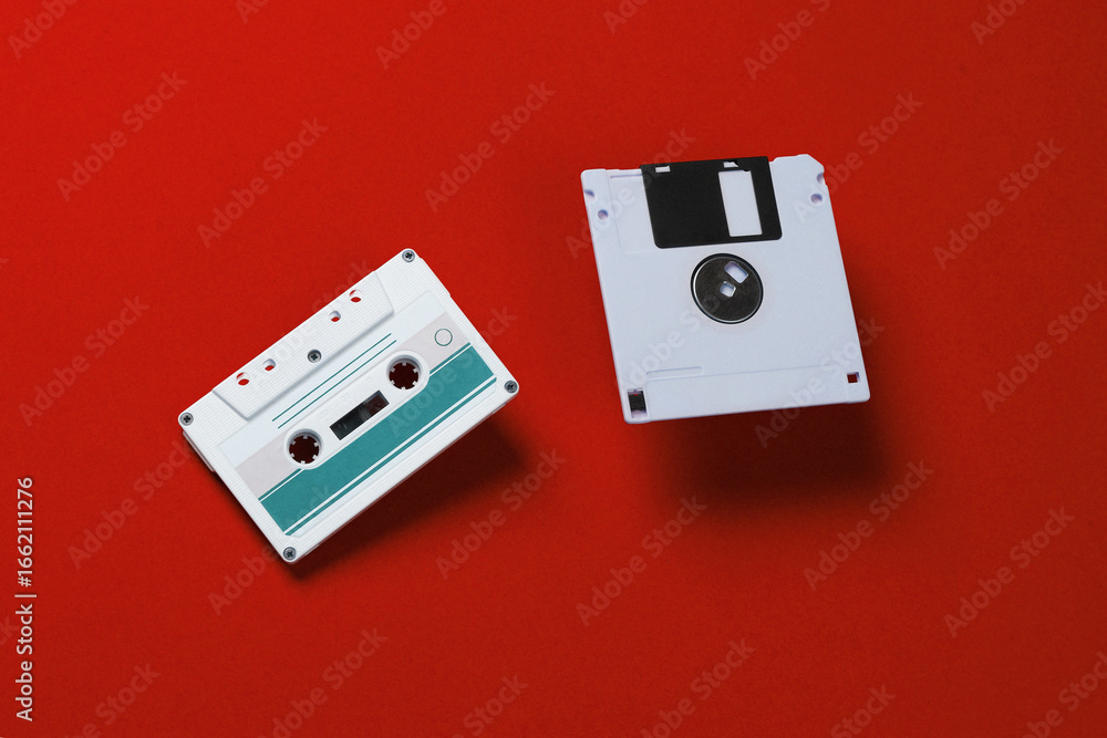 Poster white floppy disk and audio cassette on red background. retro technology. top view
