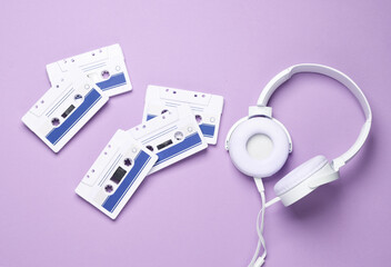 Retro 80s audio cassette with stereo headphones on purple background. Top view. Flat lay