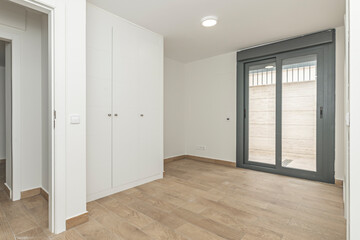 Undecorated guest room with Nordic-style white built-in wardrobes, combining plain doors and...