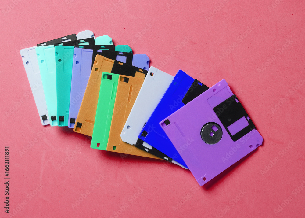 Poster Colored floppy disks on pink background. Retro technology. Top view