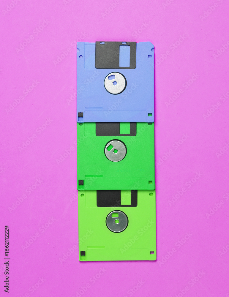 Poster colored floppy disks on a pink vivid background. top view