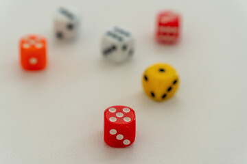 Dices in white, red, orange and yellow showing random numbers, on a white, textured canvas...