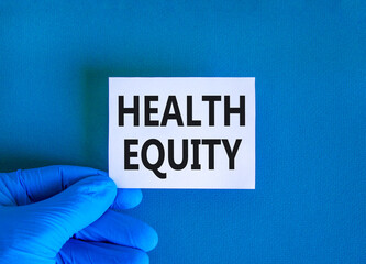 Health equity symbol. Concept words Health equity on beautiful white card. Doctor's hand in blue...