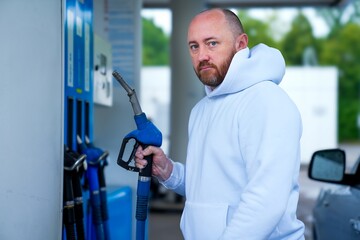 Man Holding Fuel Pump Nozzle at Gas Station